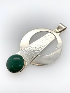 "Vintage Modernist Pendant -Unique and modern, circular pendulum design -Comprised of Sterling silver and a round bezel set malachite stone -The silver piece holding the malachite is hammered or textured, the circular piece and bail are not -Marked \"Sterling\" on the back -Bail is connected with a single pin and swivels -Larger bail to accommodate most chains, .25\" x .1\" teardrop shaped opening -Pendant measures about 2.5\" x 1.5\" -Malachite stone measures 14mm round -Total weight 9.6g -Pend Modern Polished Emerald Jewelry, Modernist Round Cabochon Jewelry, Modern Cabochon Round Pendant Jewelry, Modern Jewelry With Round Cabochon Pendant, Modern Cabochon Round Pendant, Modern Green Cabochon Jewelry, Modern Green Malachite Jewelry, Modern Green Pendant Jewelry, Modern Green Round Pendant Jewelry