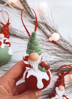 a hand holding an ornament in front of some christmas decorations on a table