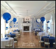 a room filled with tables and chairs covered in blue and white balloons next to a fire place