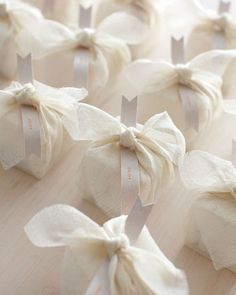 small white bags with bows tied around them on a wooden table, ready to be used as wedding favors