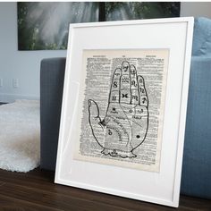 an old book page with a drawing of a hand on it in front of a couch