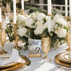 gold mirror table numbers for wedding on a white table white flowers and gold plates Elegant White And Gold Wedding Decor, Classy Wedding Flower Arrangements, Tall Flowers Wedding Table, Brass Wedding Table Decor, Dark Green And Gold Table Setting, Classic Wedding Tablescape, Classy Wedding Ideas Decor, Elegant Classy Wedding Decor