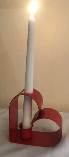 a white candle sitting on top of a red stand