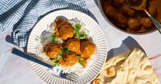 a plate with meatballs and rice on it next to a bowl of pita bread