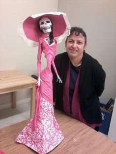 a woman sitting at a table with a paper doll in her hand and a skull on top of it