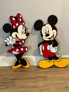 two mickey and minnie mouse cut outs on the floor in front of a white wall