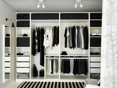 an open closet with clothes hanging on the walls and drawers, along with black and white striped rugs