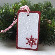 a red and white snowflake ornament hanging from a christmas tree