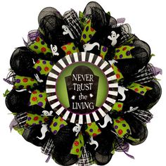 a wreath that says never trust the living with black and green decorations on it's front