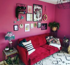 a living room with pink walls and lots of pictures on the wall above the couch