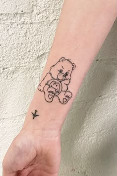 a small tattoo on the wrist of a person with a teddy bear holding a bird