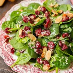 spinach salad with cranberries and almonds on a red and white plate