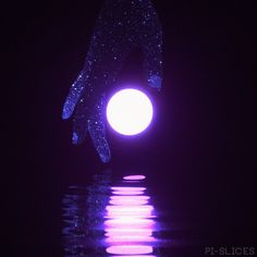 a person's hand reaching for a glowing ball in the water at night time