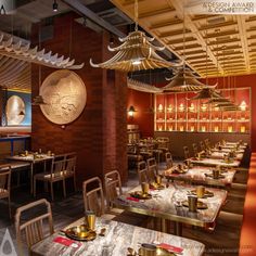 the interior of a restaurant with many tables and chairs, gold dishes on top of them