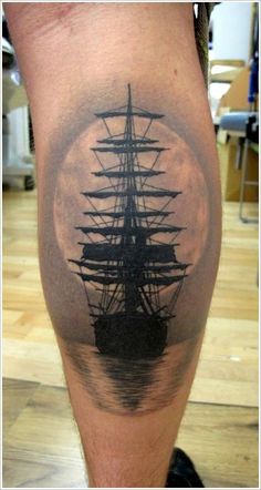 a man's leg with a ship tattoo on it