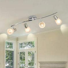 three lights are hanging from the ceiling above a bed in a room with white walls and windows