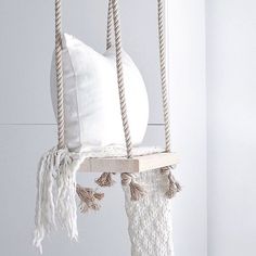 a white pillow hanging from a rope with tassels