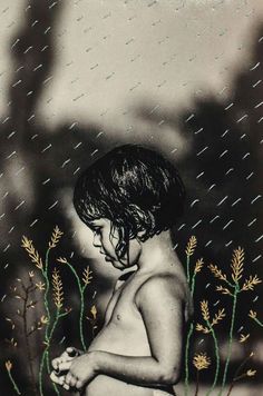 a young boy sitting in the rain with his hands clasped to his knees and looking down