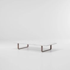 a white marble coffee table with metal legs on a plain surface in an empty room