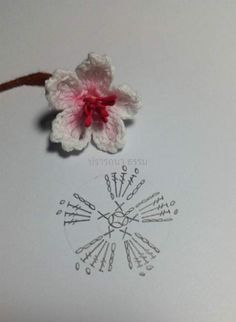 a crocheted flower and needles on a piece of paper