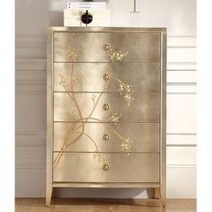 a gold and silver dresser with flowers painted on the front, in a living room