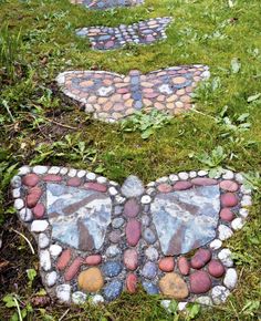 two butterfly stepping stones in the grass, one is made out of rocks and the other has