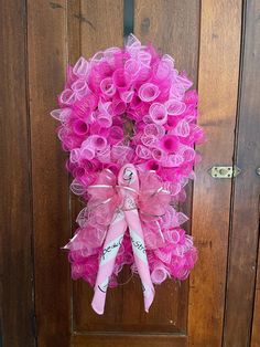 a pink wreath is hanging on the front door