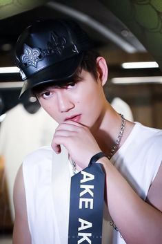 a young man wearing a black hat and white shirt with an ake ake sash around his neck