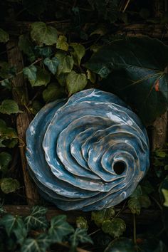 a blue vase sitting on top of green leaves