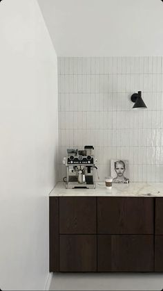 a white tiled wall in a kitchen next to a counter with two coffee makers on it