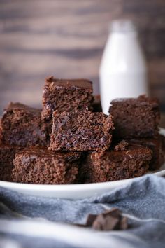 a white bowl filled with brownies next to a bottle of milk