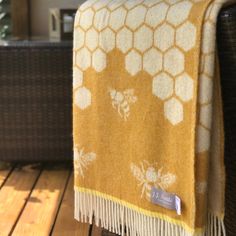 a yellow and white blanket sitting on top of a wooden floor next to a wicker chair