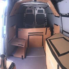 the inside of an empty van with cardboard boxes on the floor and shelves in the back