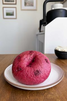 a pink donut sitting on top of a white plate