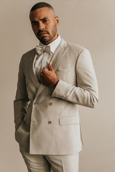 a man in a suit and bow tie poses for a photo with his hands on his chest