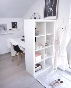 a white closet with clothes hanging on the wall and shoes sitting on the floor in front of it