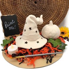 a witches hat, candle and pumpkin on a table next to a wicker basket