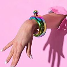 a woman's arm with a ring on it, casting a shadow against a pink background