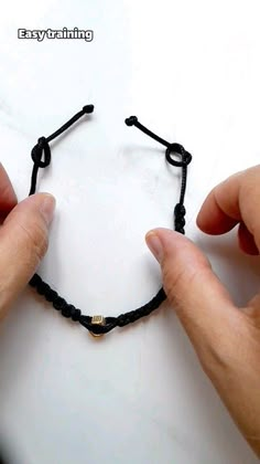 two hands are holding black string bracelets