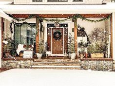 a house covered in snow with christmas wreaths on the front door and steps leading up to it