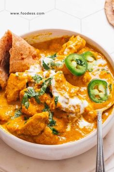 a white bowl filled with chicken curry and pita bread