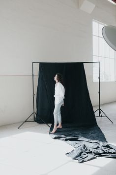 a woman is standing in front of a black backdrop while she stands on the floor