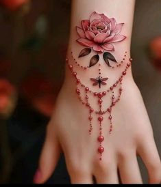 a woman's hand with a pink flower tattoo on the wrist and rosarys attached to it