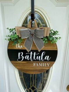 a wooden sign that says the battula family hanging on a door with plants