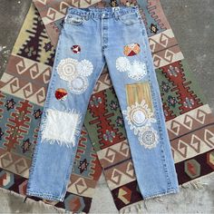 an old pair of jeans with patches and flowers on them sitting on a rug in front of a wall