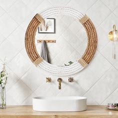 a white sink sitting under a round mirror in a bathroom next to a wooden counter