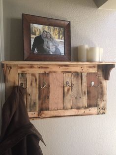 a wooden shelf with two pictures on it and some candles in front of the wall