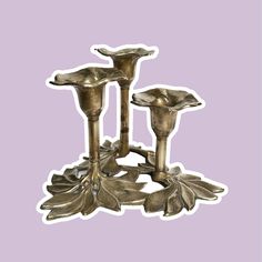 three metal candlesticks sitting next to each other on top of a purple background