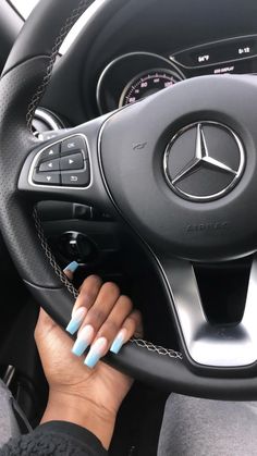 the woman is driving her car with blue and white nails