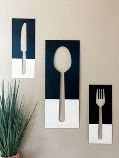 three pieces of artwork on the wall with forks and spoons attached to them, in front of a potted plant